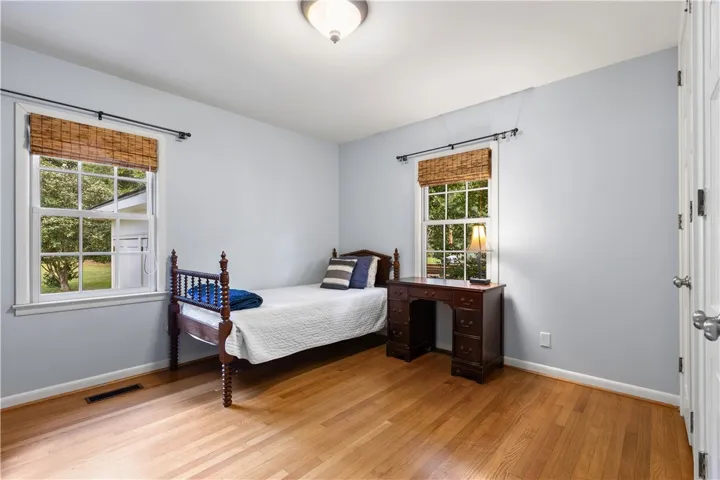 Polished hardwood floors and 2 windows anchor this large bedroom.
