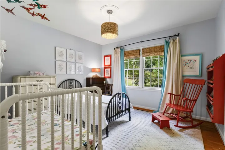 Two windows overlook the spacious backyard beyond this large wood-floored bedroom.
