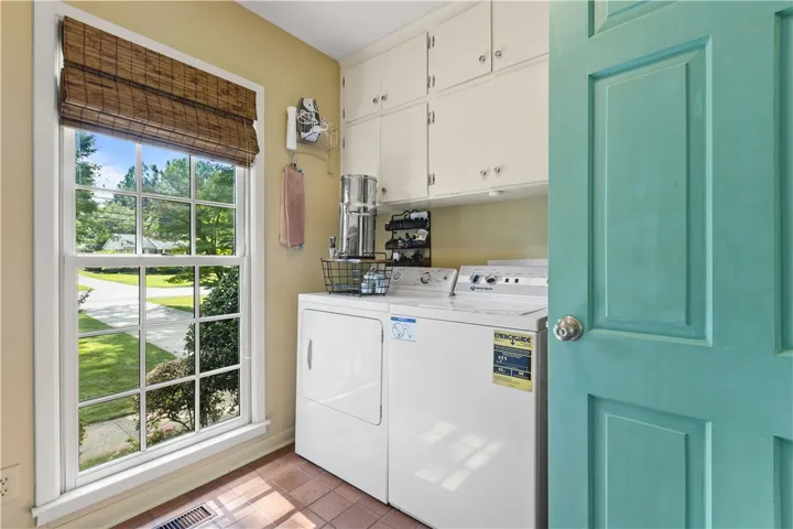 A window brings natural light into this laundry room, which also offers ample cabinet storage.