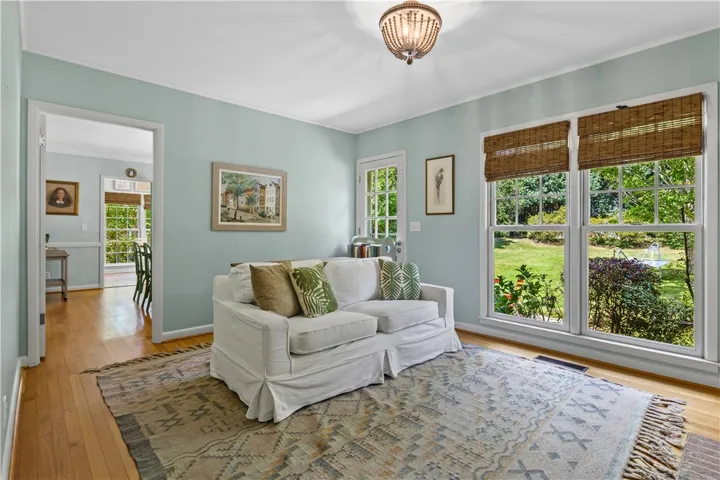 Polished hardwood floors and generous windows framing green backyard views enhance this welcoming den space.