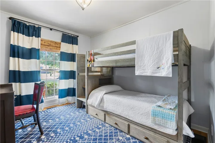 Crown molding and a large window enhance this comfortable bedroom space.