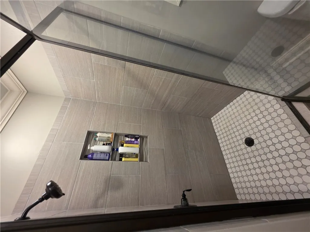 Floor-to-ceiling tiling and a modern glass enclosure define this walk-in shower.