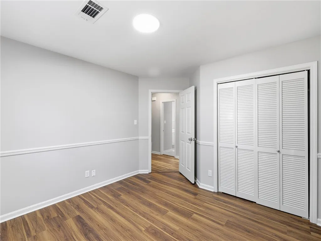Warm wood-look flooring and classic chair rail molding define this versatile bedroom space.