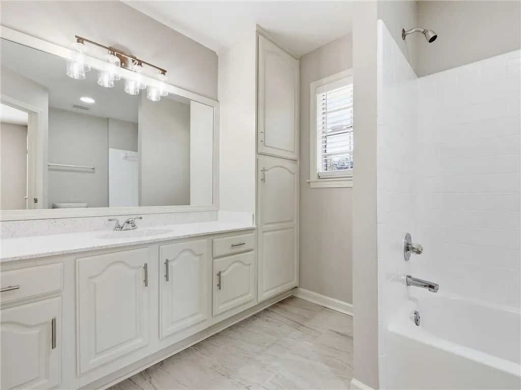 An integrated vanity, custom cabinetry, and neutral tile define this pristine bathroom.