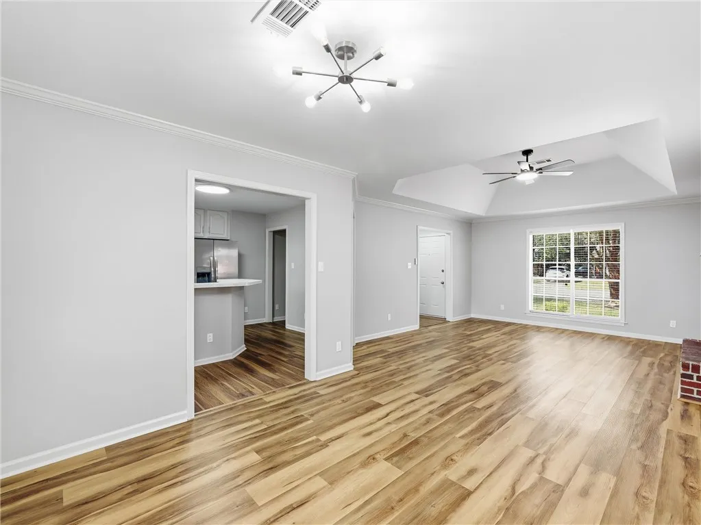 An open floorplan connects the living area to the kitchen over handsome wood-style flooring.