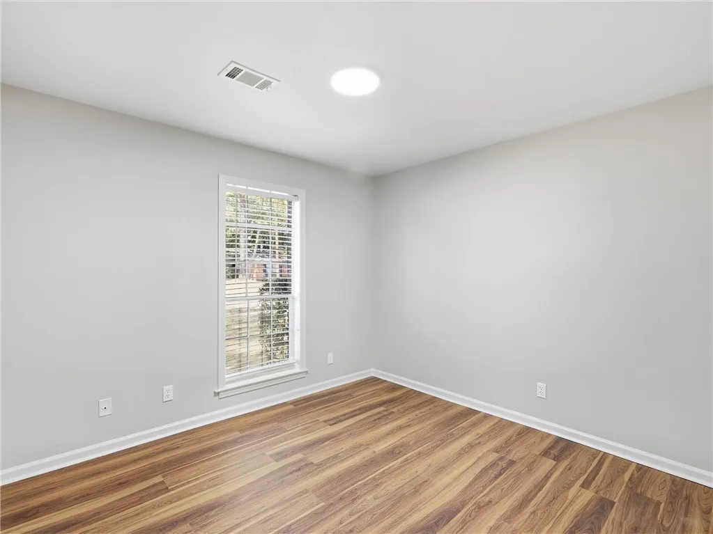 Rich wood-look flooring sets a warm foundation in this versatile empty bedroom.