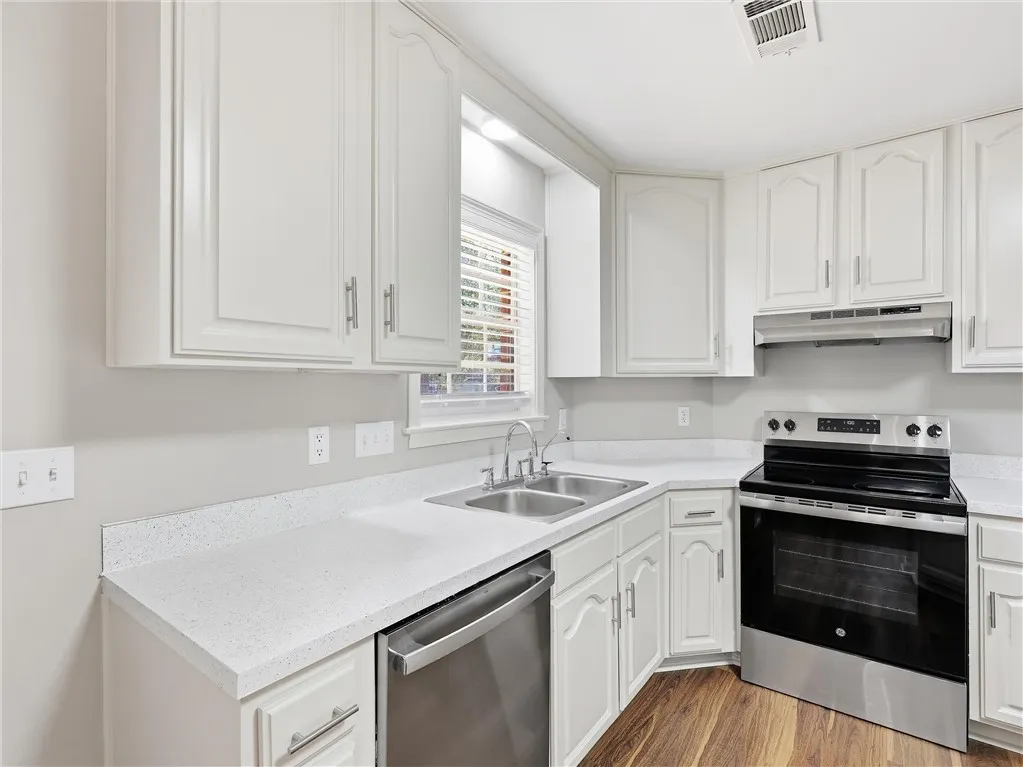Ample cabinetry and stone countertops frame this well-appointed workspace with rich wood-style flooring.