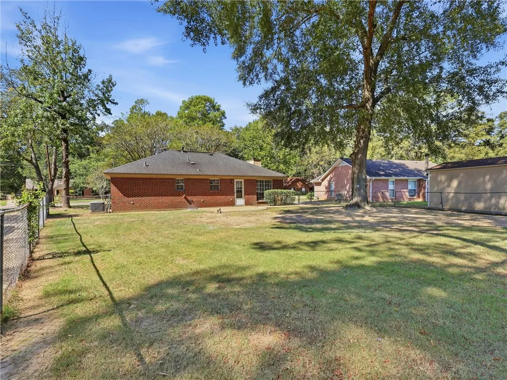 Mature trees shade a spacious back lawn framed by classic brick architecture.
