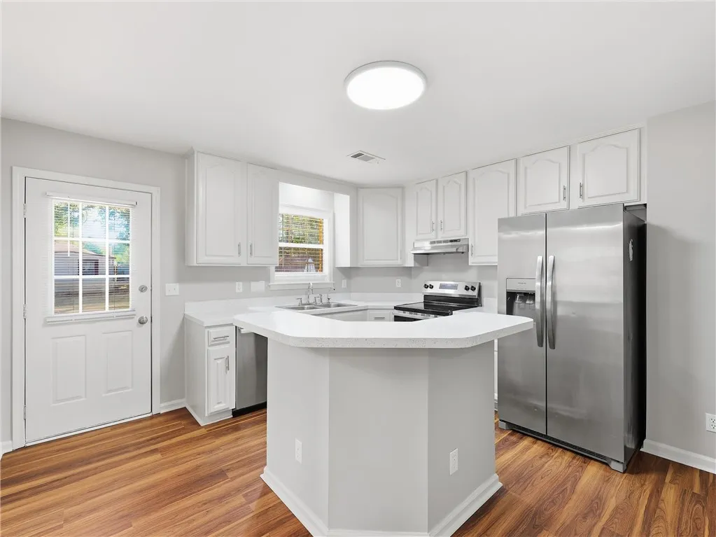 Gleaming hardwood floors and a central prep island anchor this updated culinary space.