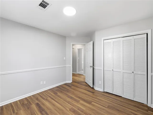 Warm wood-look flooring and classic chair rail molding define this versatile bedroom space.