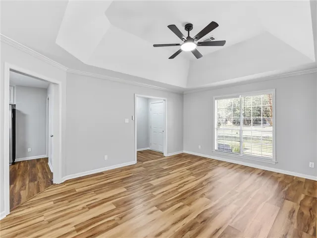 Rich wood flooring contrasts beautifully with crisp white trim and a recessed tray ceiling.