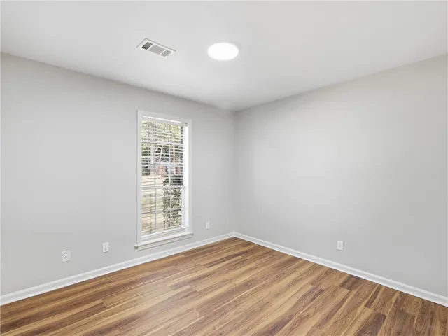 Rich wood-look flooring sets a warm foundation in this versatile empty bedroom.