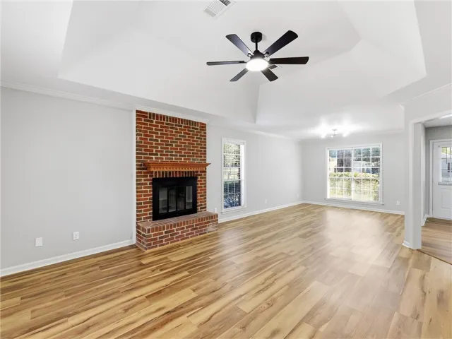 A classic brick fireplace anchors the living room beneath a soaring tray ceiling.
