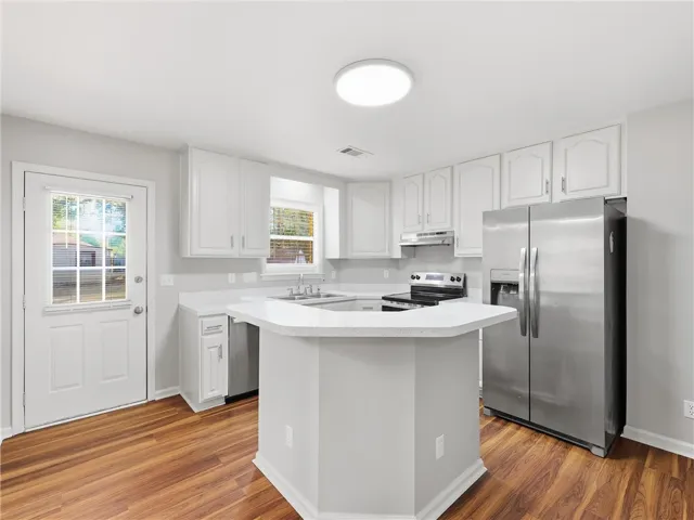 Gleaming hardwood floors and a central prep island anchor this updated culinary space.
