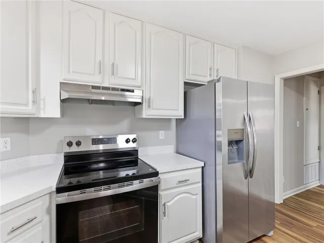 Gleaming stainless steel appliances complement the classic white cabinetry and crisp solid surface countertops.