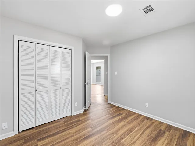 Rich wood-look flooring and crisp white trim enhance this versatile bedroom space.