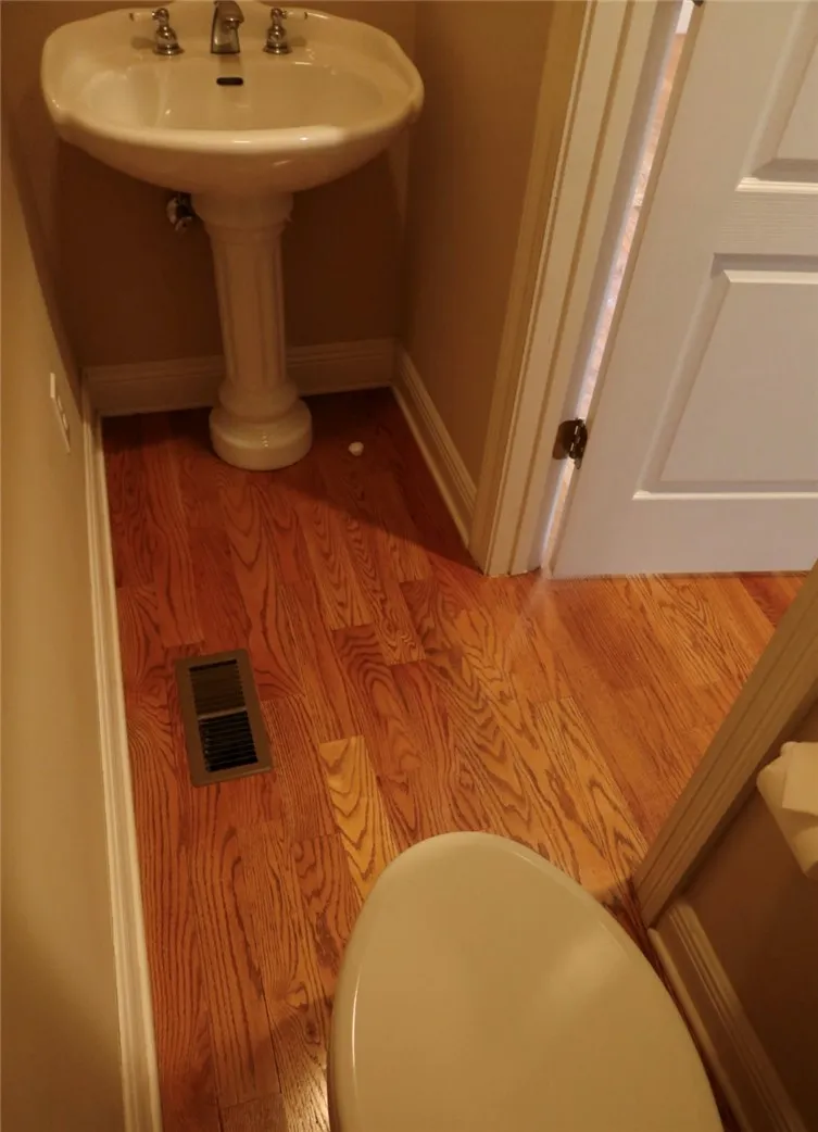 Rich hardwood flooring pairs beautifully with classic moldings in this powder room.