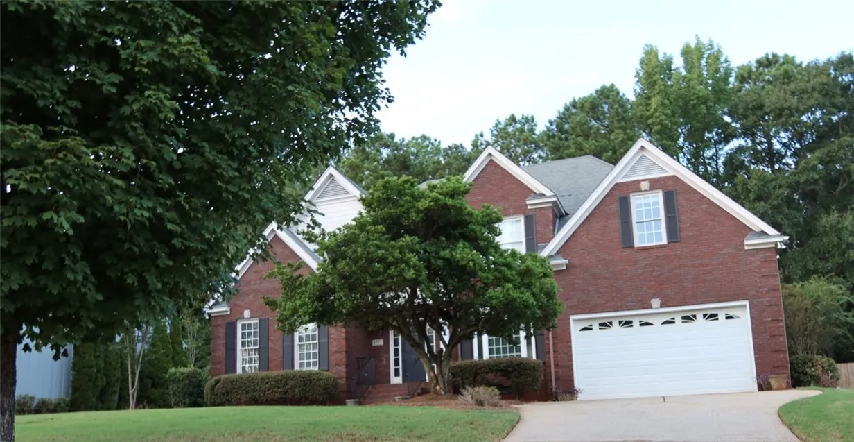 Stately brick exterior featuring multiple gables and a spacious two-car garage under mature trees.