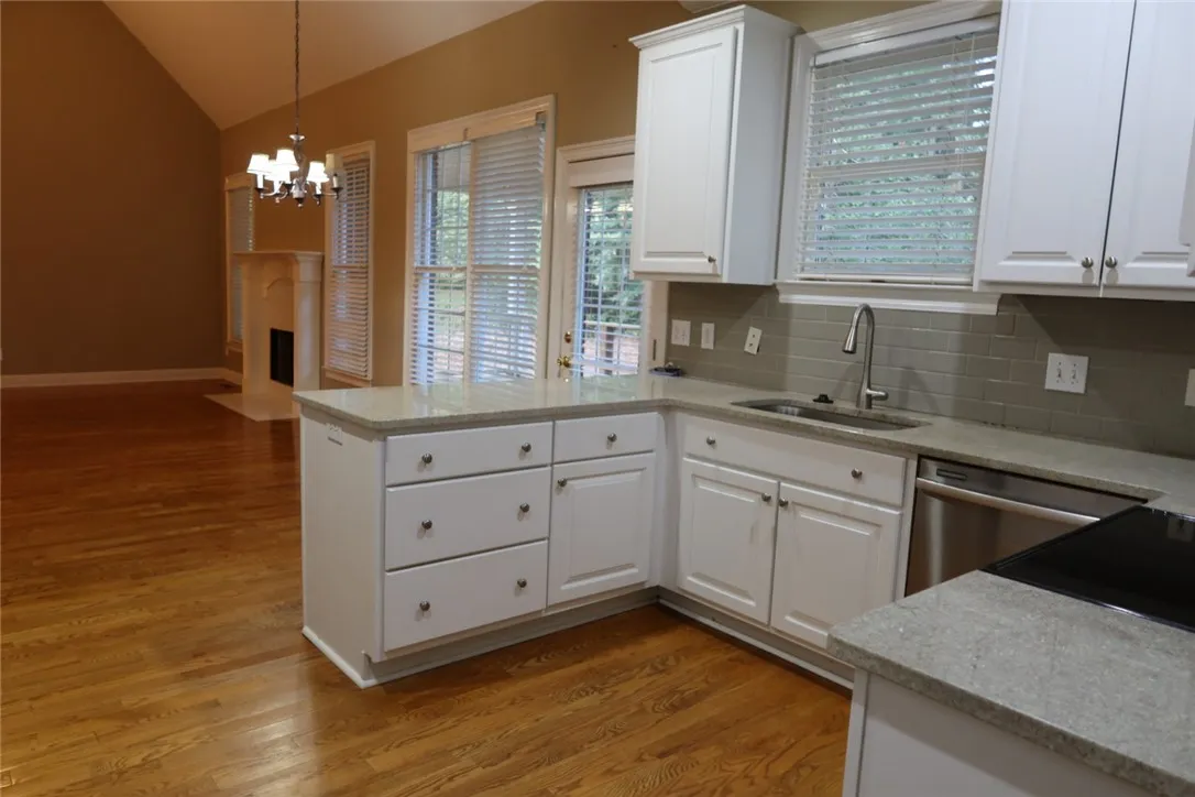 Rich hardwood flooring anchors this open kitchen layout leading directly to the fireplace-warmed living space.
