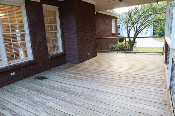Rich brick accents surround a covered wooden deck looking out toward the peaceful yard.