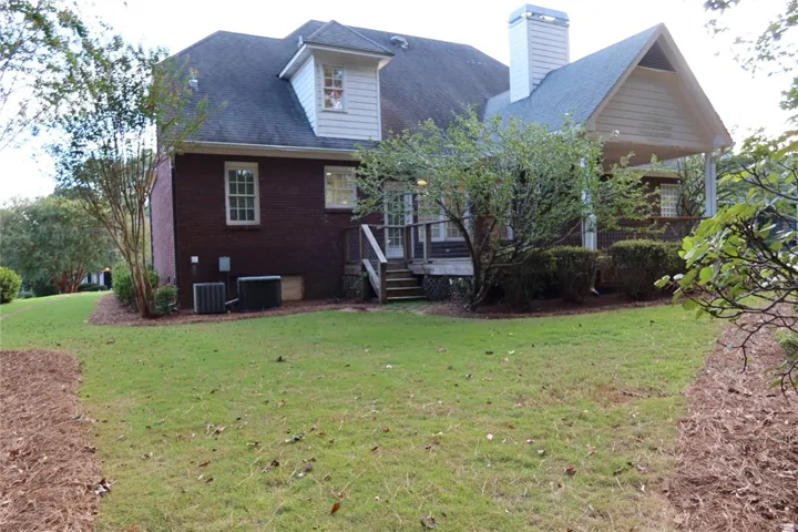 A spacious grassy lawn borders the rear of this classic brick and siding residence.