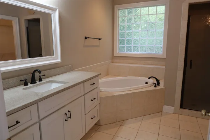 A corner soaking tub and tile floors highlight this classic master bathroom setup.