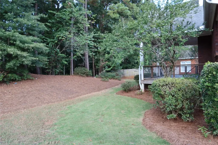 Mature trees and landscaping frame the backyard space adjacent to the elevated wooden deck.