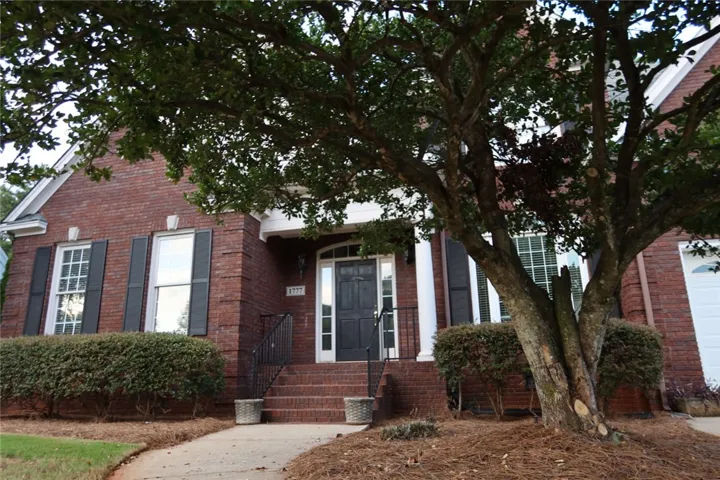 Mature trees shade the classic brick exterior and welcoming entryway of this handsome home.
