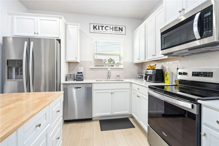 Crisp white cabinetry paired with modern stainless steel appliances highlights this efficient kitchen workspace.
