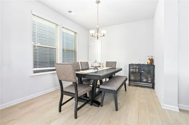Natural light pours through dual windows, highlighting the light wood flooring in this dining area.