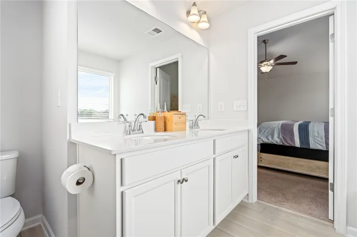 Clean lines and a spacious double vanity define this bright bathroom with wood-look tile flooring.