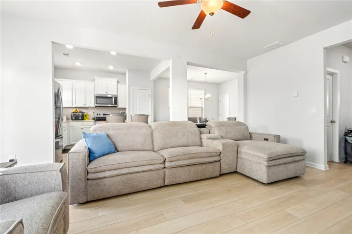 An open-concept living area flows seamlessly into the kitchen over modern wood-look flooring.