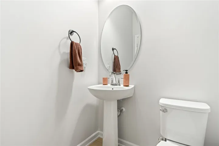 A classic pedestal sink pairs with an oval mirror in this clean powder room.