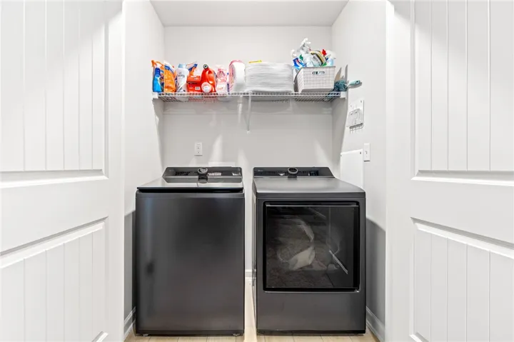 An organized laundry closet features clean white walls and durable light-toned flooring.