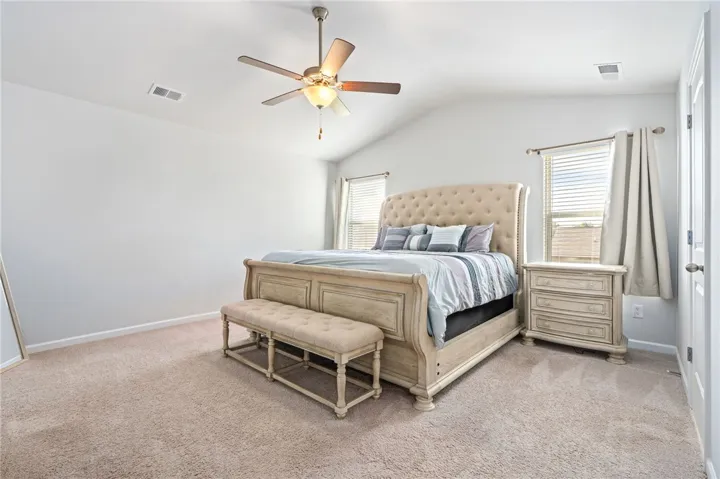 Plush carpeting and vaulted ceilings enhance this serene main floor bedroom retreat.