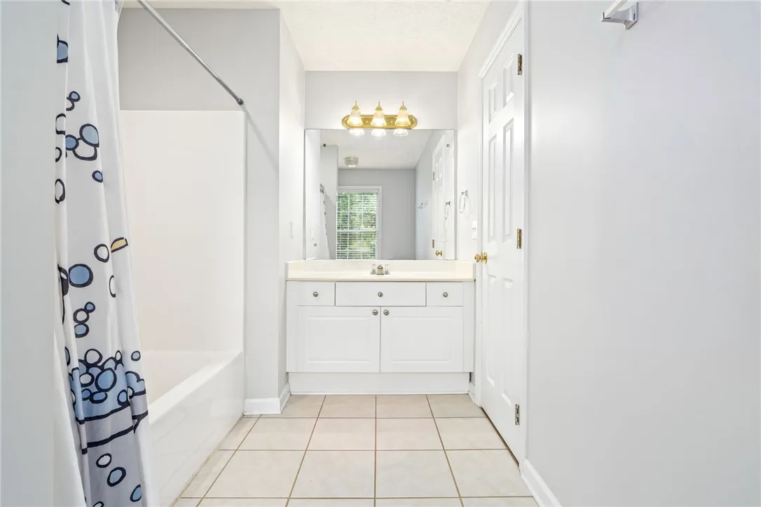 Tiled flooring and a crisp white vanity complete this functional bathroom space.