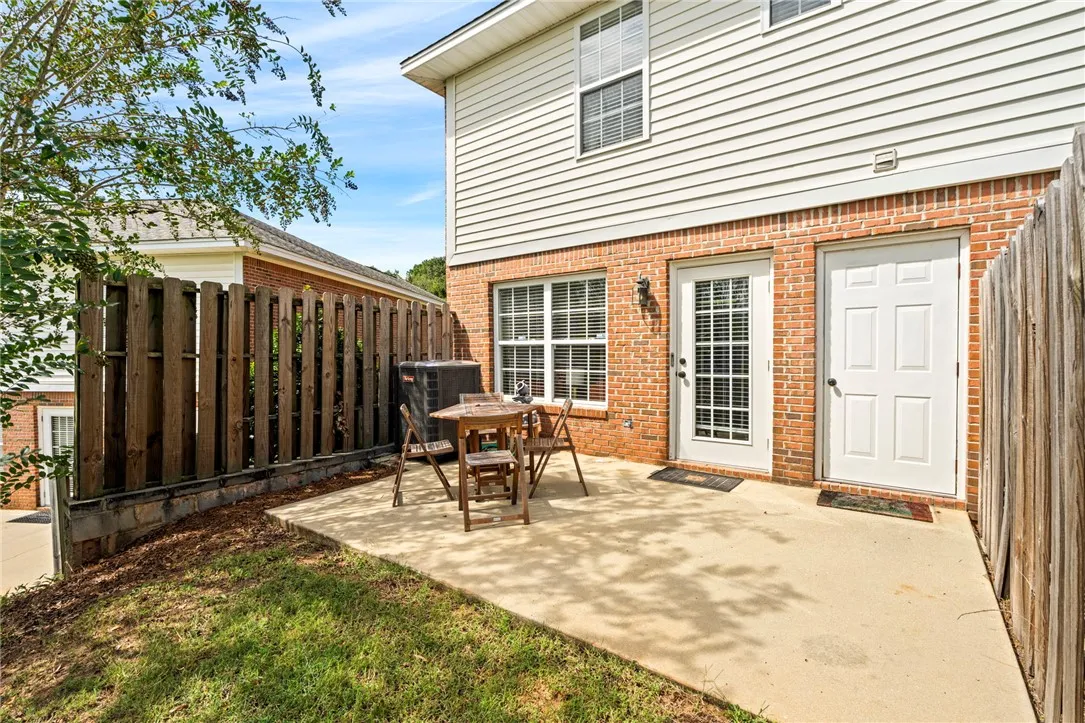 A private concrete patio sits enclosed by wood fencing along the brick exterior wall.