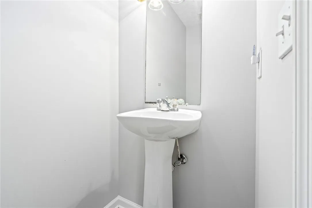 A classic pedestal sink sits beneath a simple wall-mounted mirror in this compact half bath.