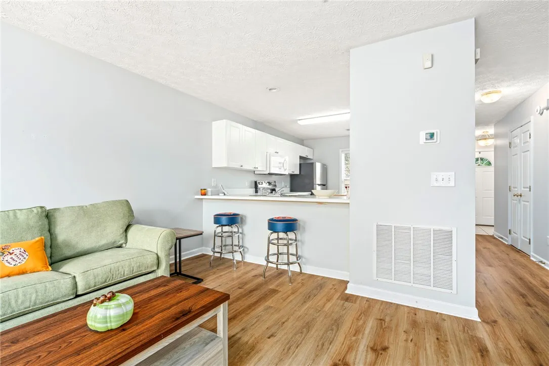 Warm wood flooring flows from the living area directly into the open kitchen space.