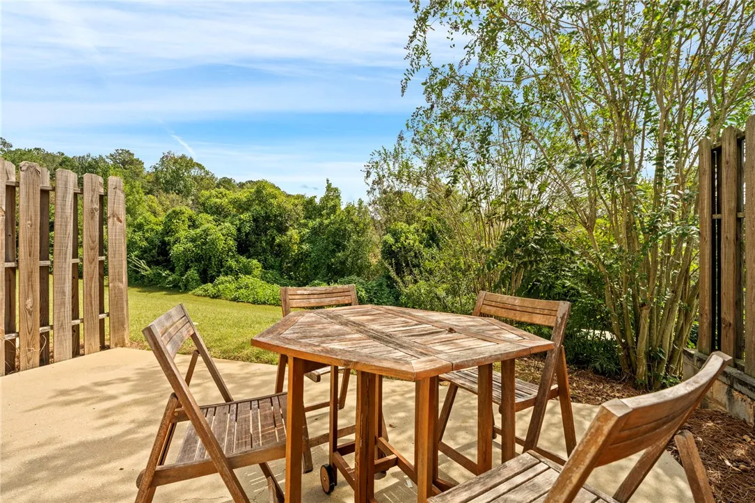 A concrete patio borders a grassy yard enclosed by wooden fencing.