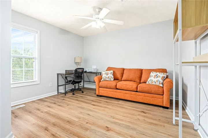 Warm wood flooring grounds this versatile room filled with natural light from a large window.