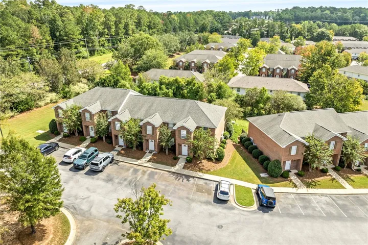 Lush mature trees surround this brick-accented multi-unit residential community with ample parking.