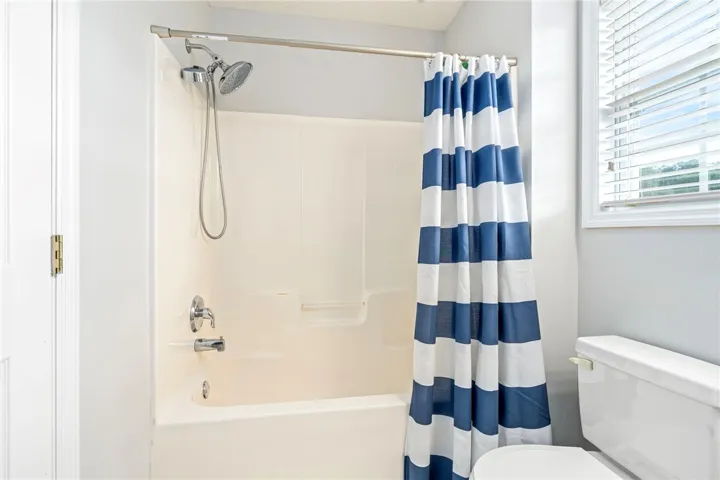 Natural light streams through a large window, illuminating this functional tub and shower combination setup.