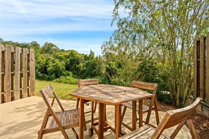 A concrete patio borders a grassy yard enclosed by wooden fencing.