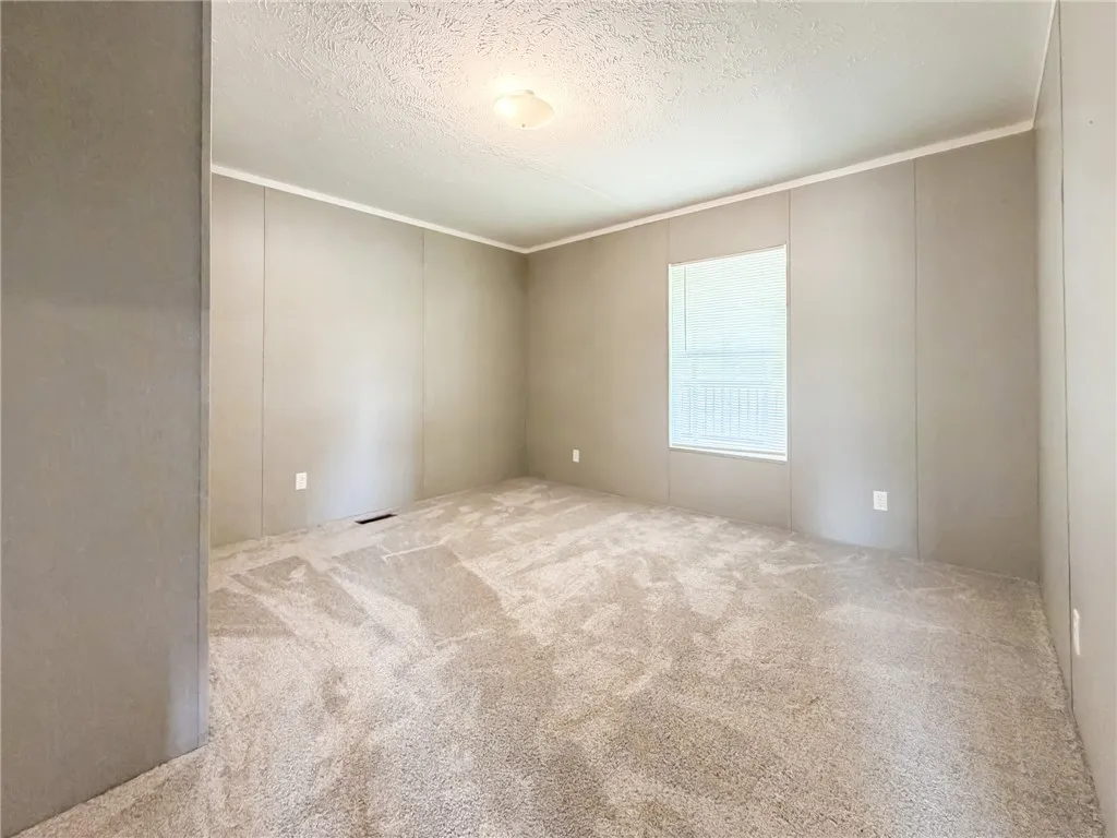 Plush wall-to-wall carpeting and a bright window define this versatile bedroom space.