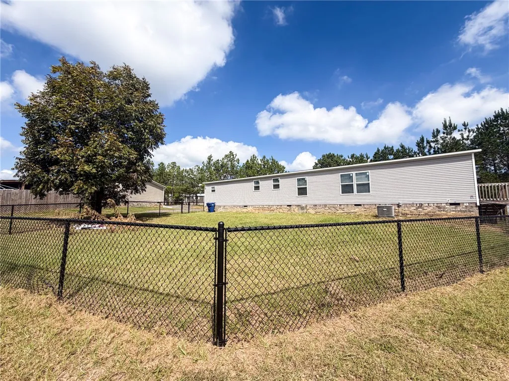 A spacious, chain-link fenced yard surrounds the rear exterior of this siding-clad home.