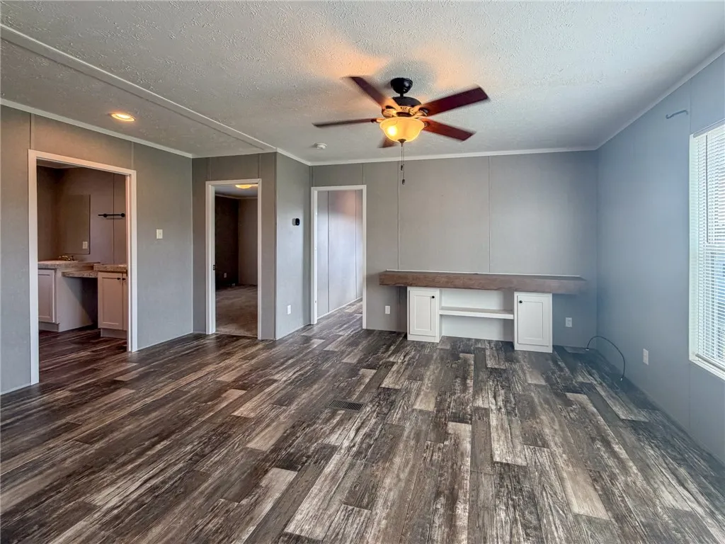 Rich wood-look flooring stretches across an open living area featuring built-in cabinetry.