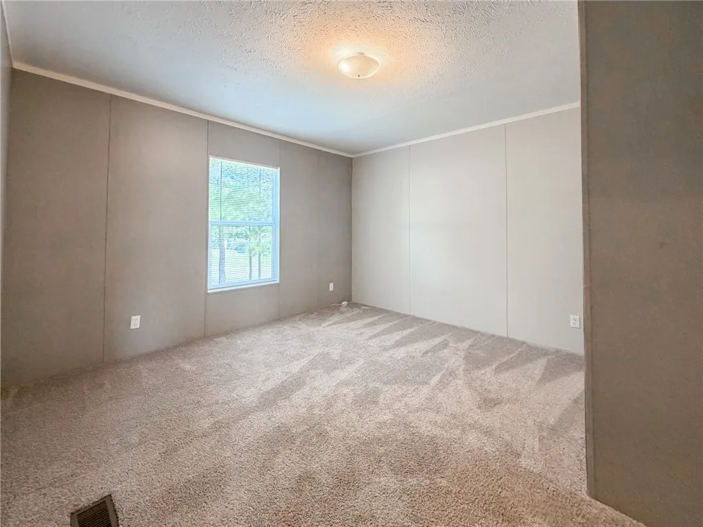 Plush wall-to-wall carpeting and a bright window define this versatile secondary bedroom space.