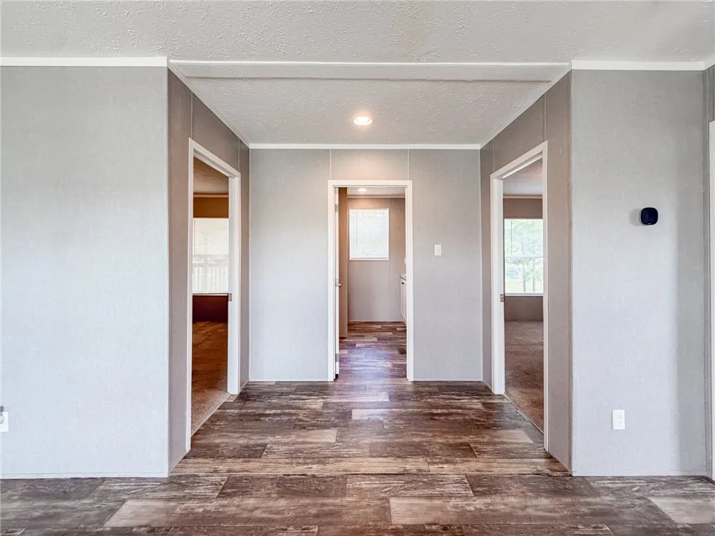 A symmetric hallway layout displays textured wood flooring leading to three separate rooms.
