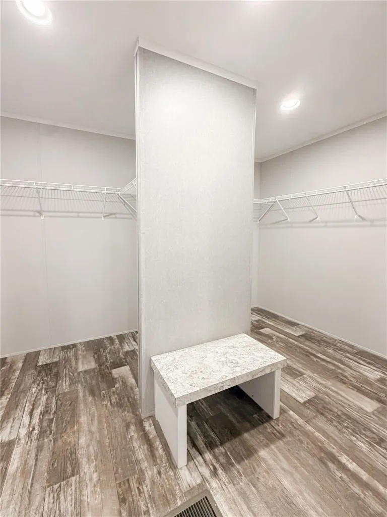 An integrated bench seat and wire shelving maximize storage within this well-lit walk-in closet.